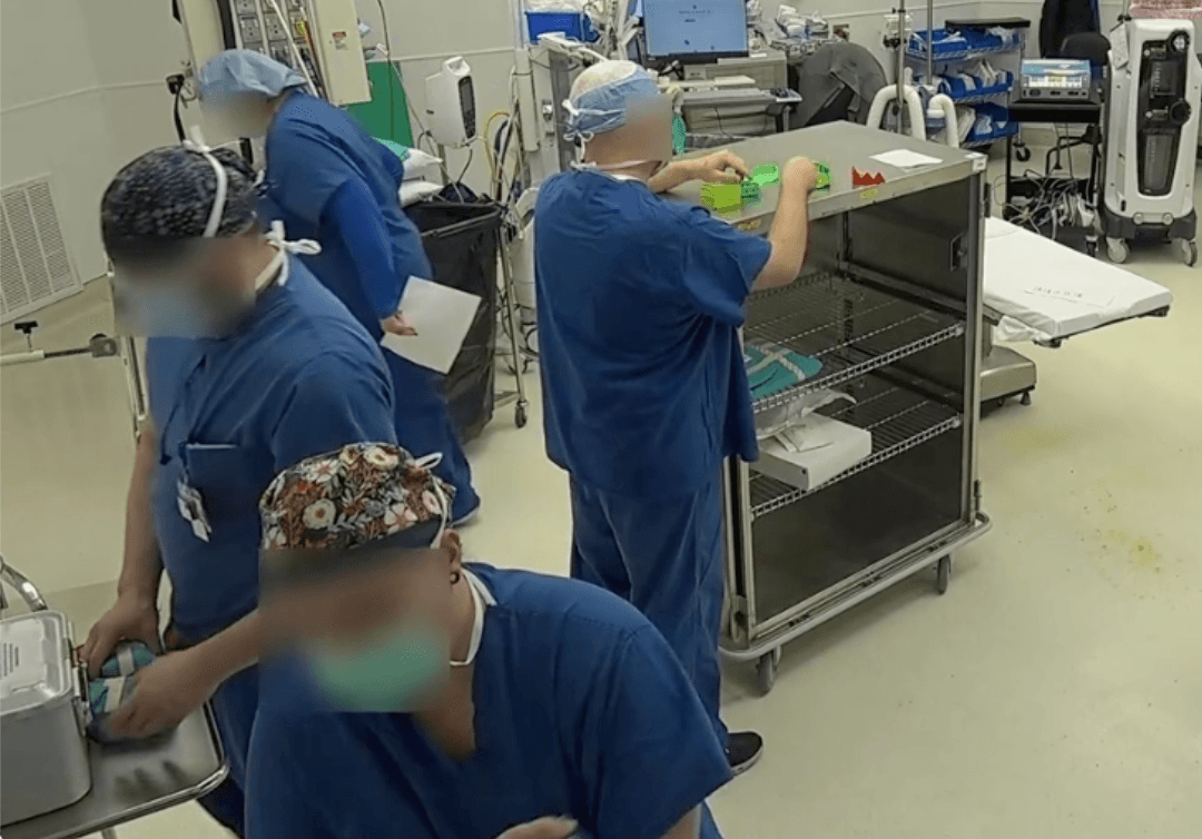 Operating room scene showing anonymized clinical staff and equipment during OR setup